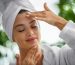 Young woman massaging face with her eyes closed. She's in the bathrobe and her hair is wrapped in the towel.